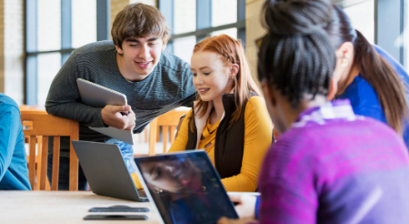 Four students reviewing computer science work on laptops 